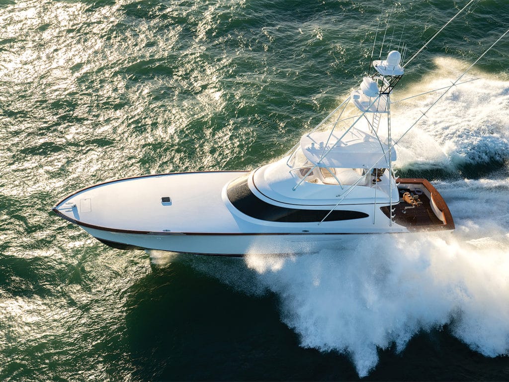 A white sport fishing boat splashes through the waves of the ocean.