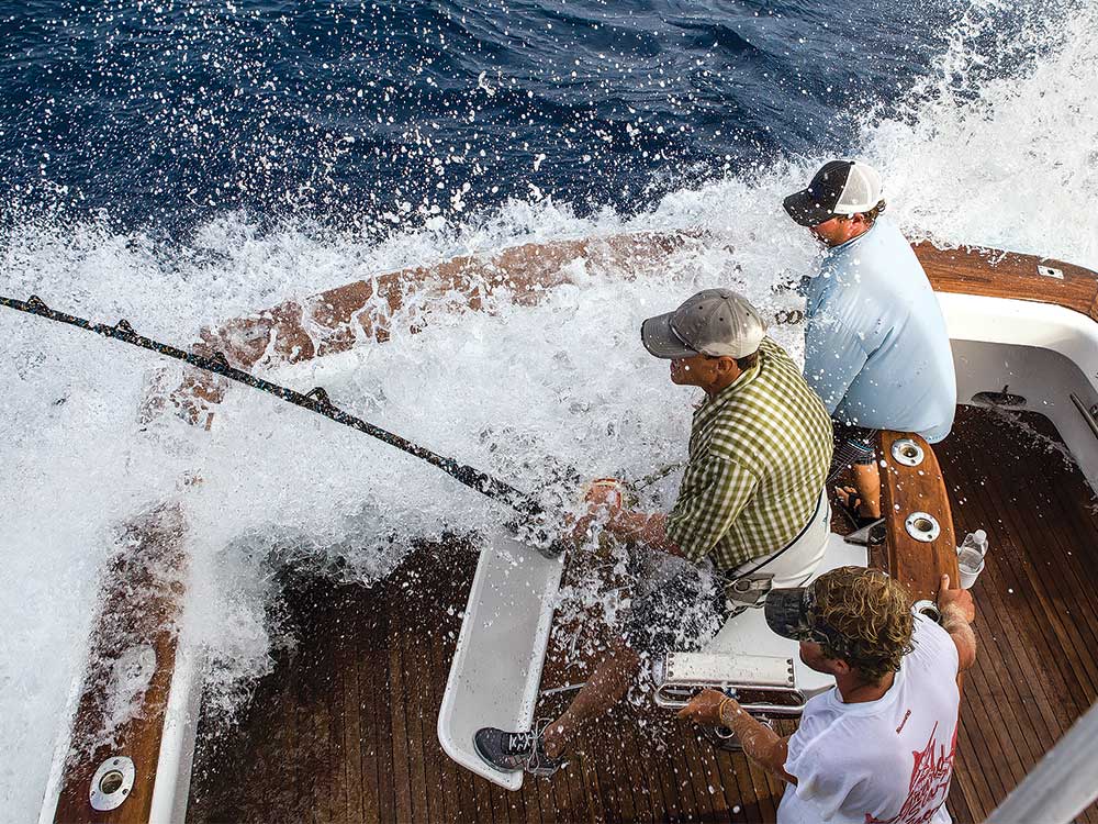 man fishing while waves splash on the boat