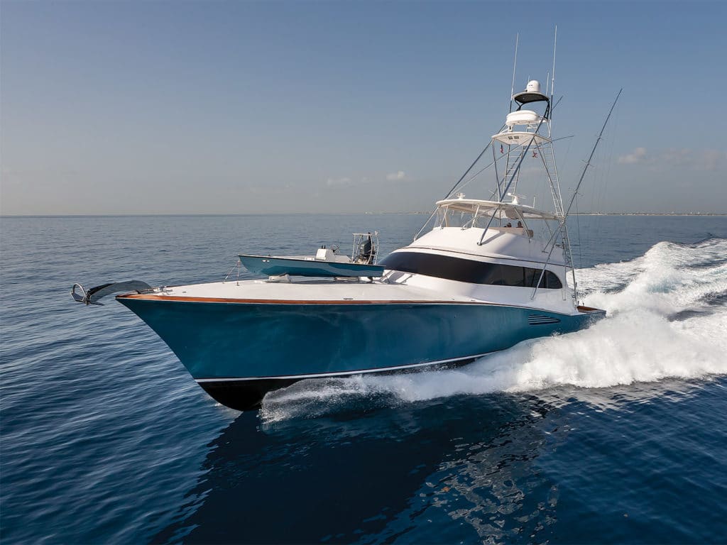 A sport-fishing boat on the water with a skiff attached.