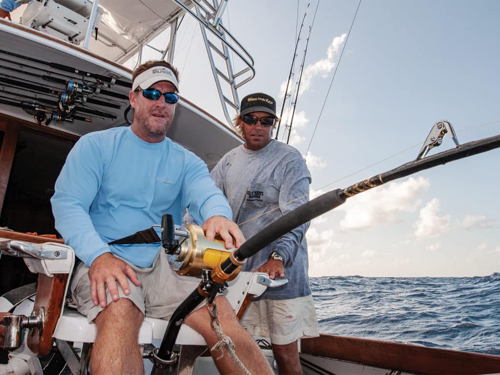 Two men sit on a sport fishing deck.