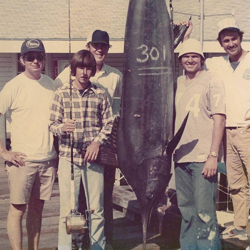 An antique photo of a fishing crew standing around a marlin.