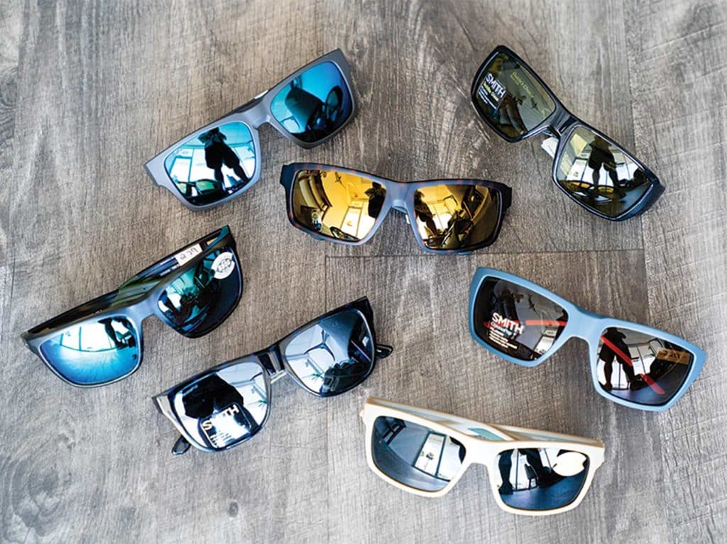 A collection of sunglasses on a wooden deck.