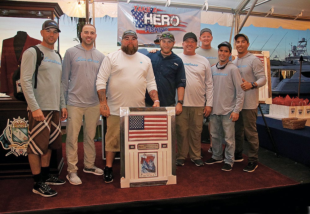 group of men standing behind flag plaque at fishing tournament