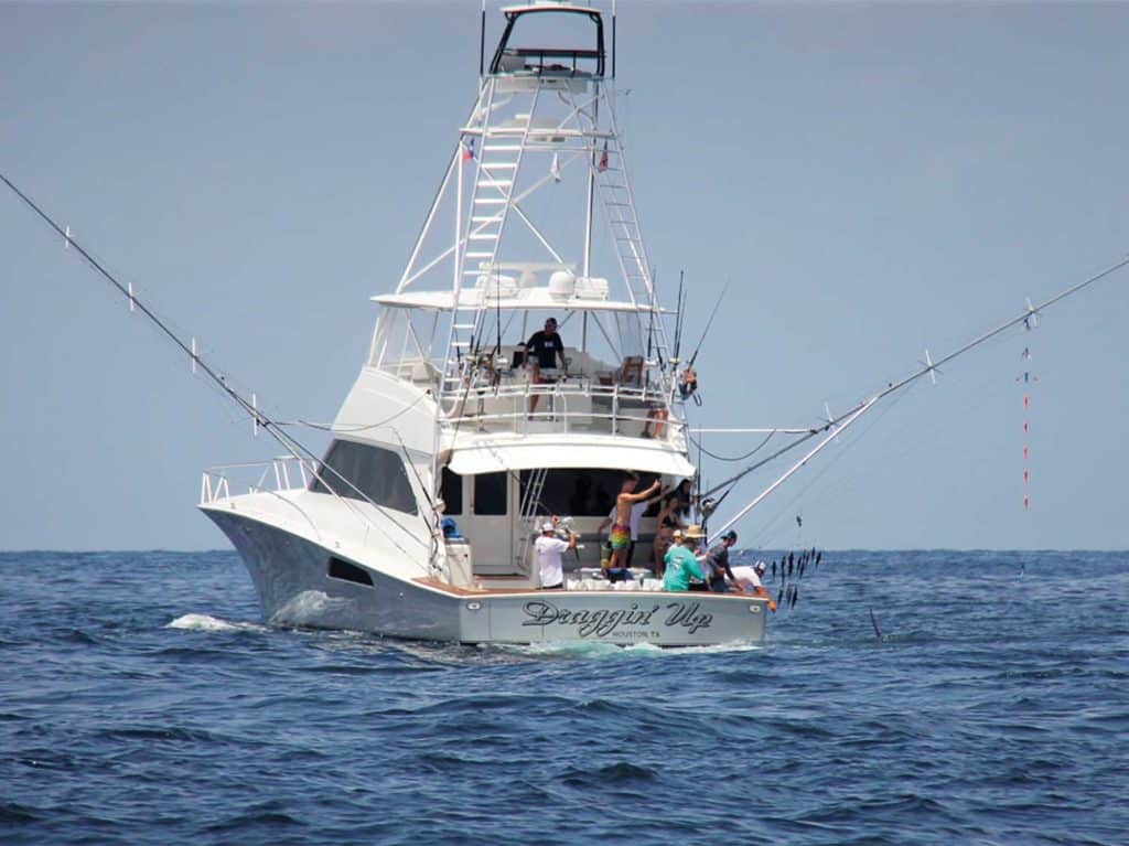 A sport-fishing boat on the water. A team fishes off the boat deck.
