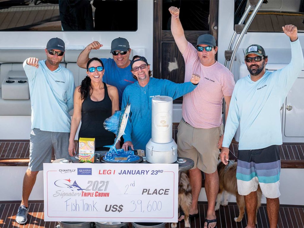 A sport-fishing team holds up their prize info while posing for a photo.