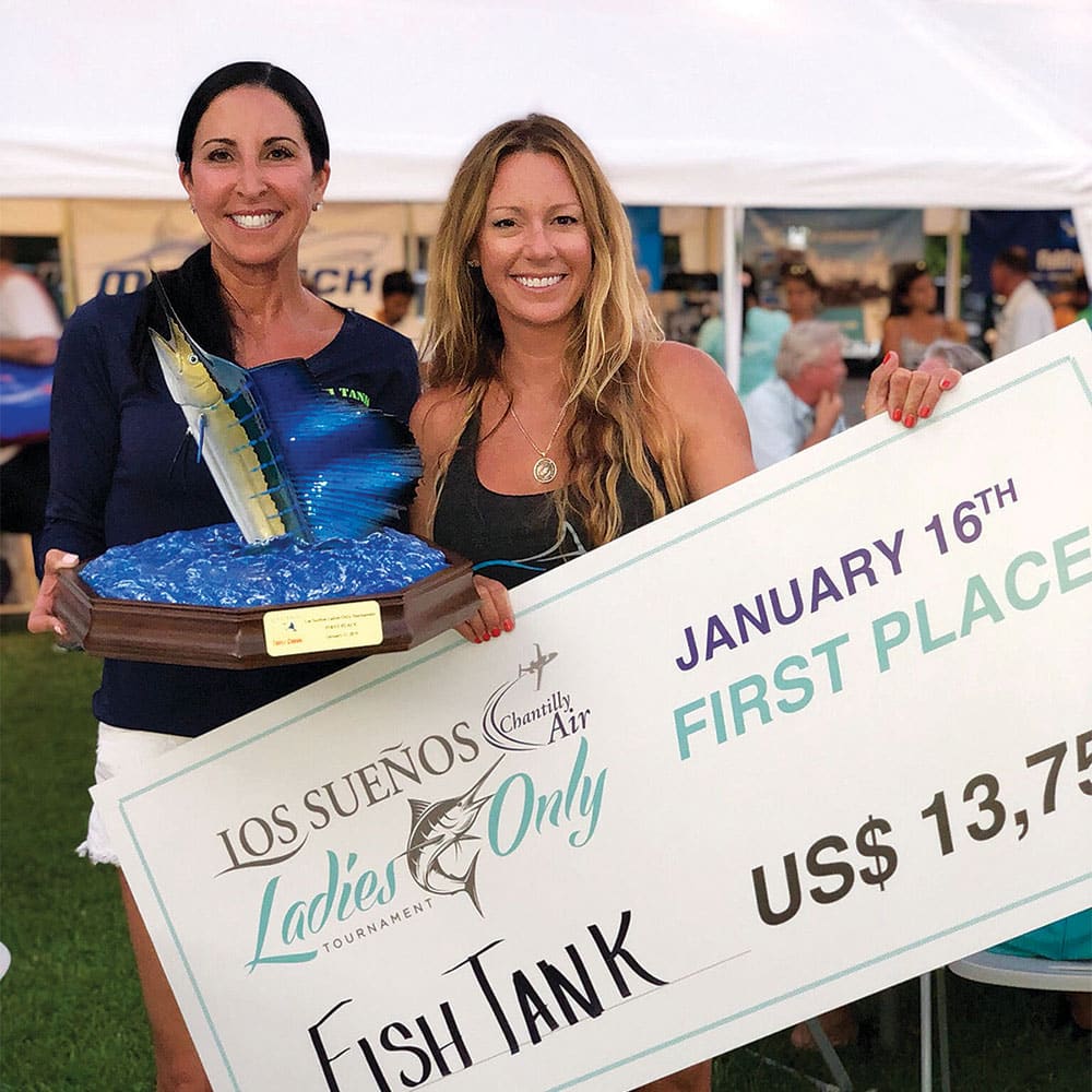 two women holding up a first place check and trophy