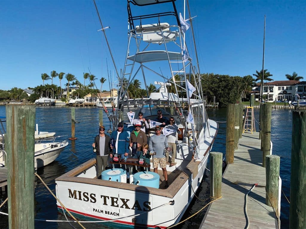 A sport fishing boat with the crew and anglers standing on its deck.