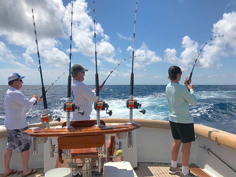 three men fishing off the side of a boat