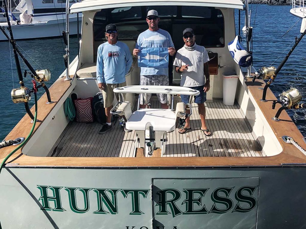three anglers standing on the boat deck of a sport fishing yacht
