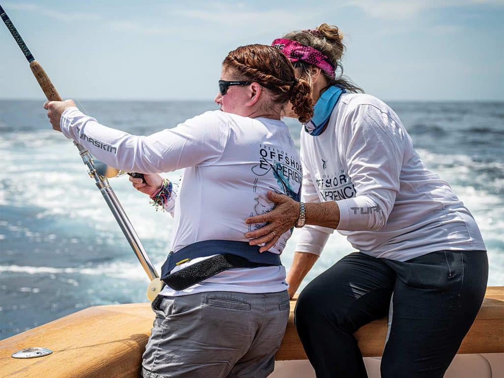 Two women fishing in the cockpit of a sport-fishing boat.
