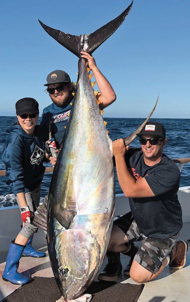 Anglers holding up a large yellowfin tuna.