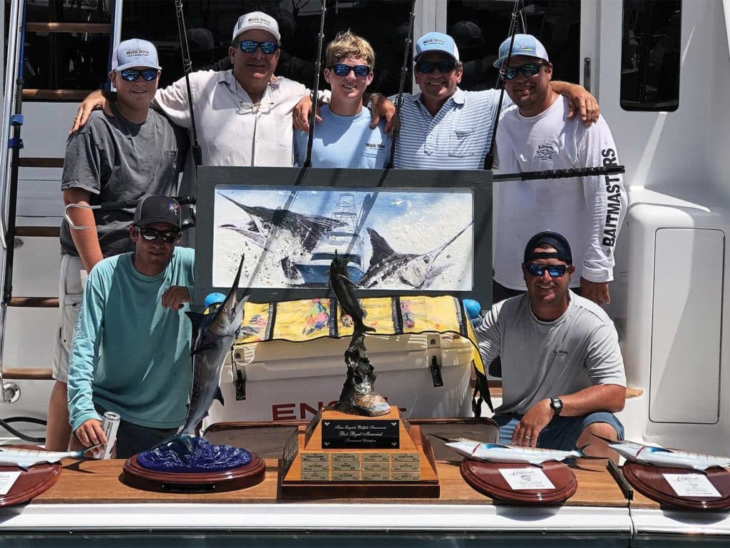 A sport-fishing team surrounded by awards.
