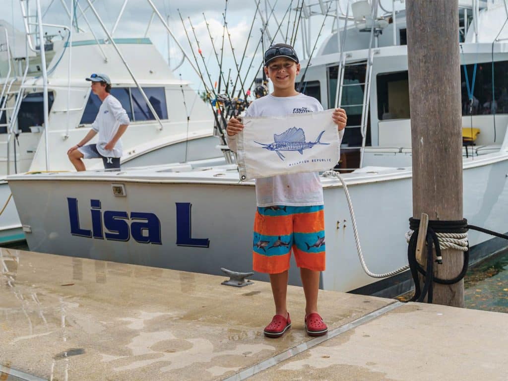 A young fishing holding up a marlin flag.