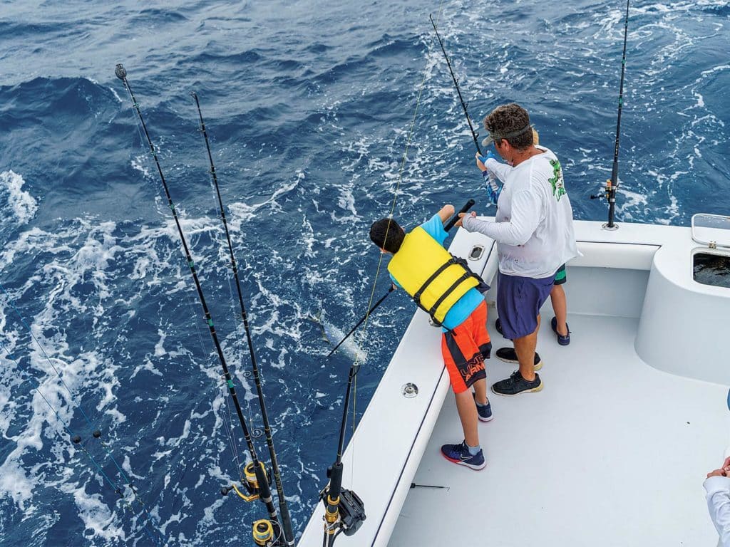 Angler teaching two young boys how to fish.