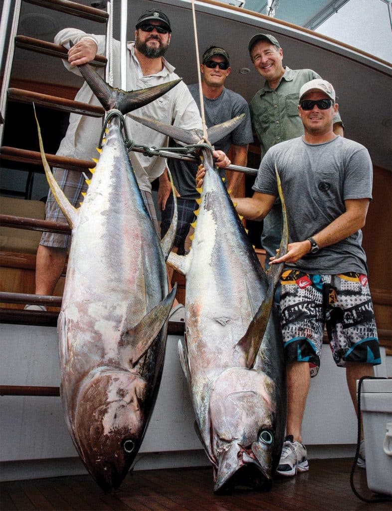 A group of anglers holding up large yellowfin tuna.