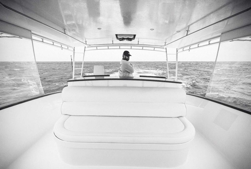 A black and white image of a boat captain at the helm.