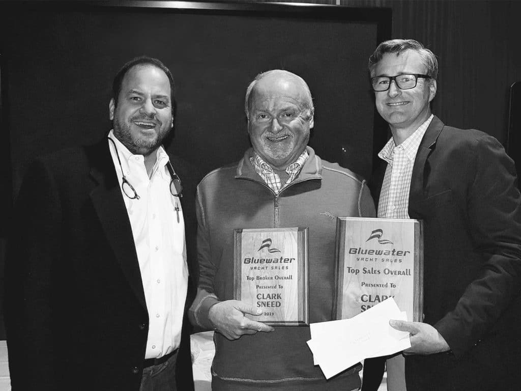 A black and white photo of three people standing and holding papers.