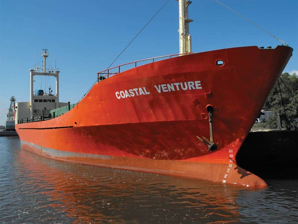 A large red barge with the words "Coastal Venture" on the side.