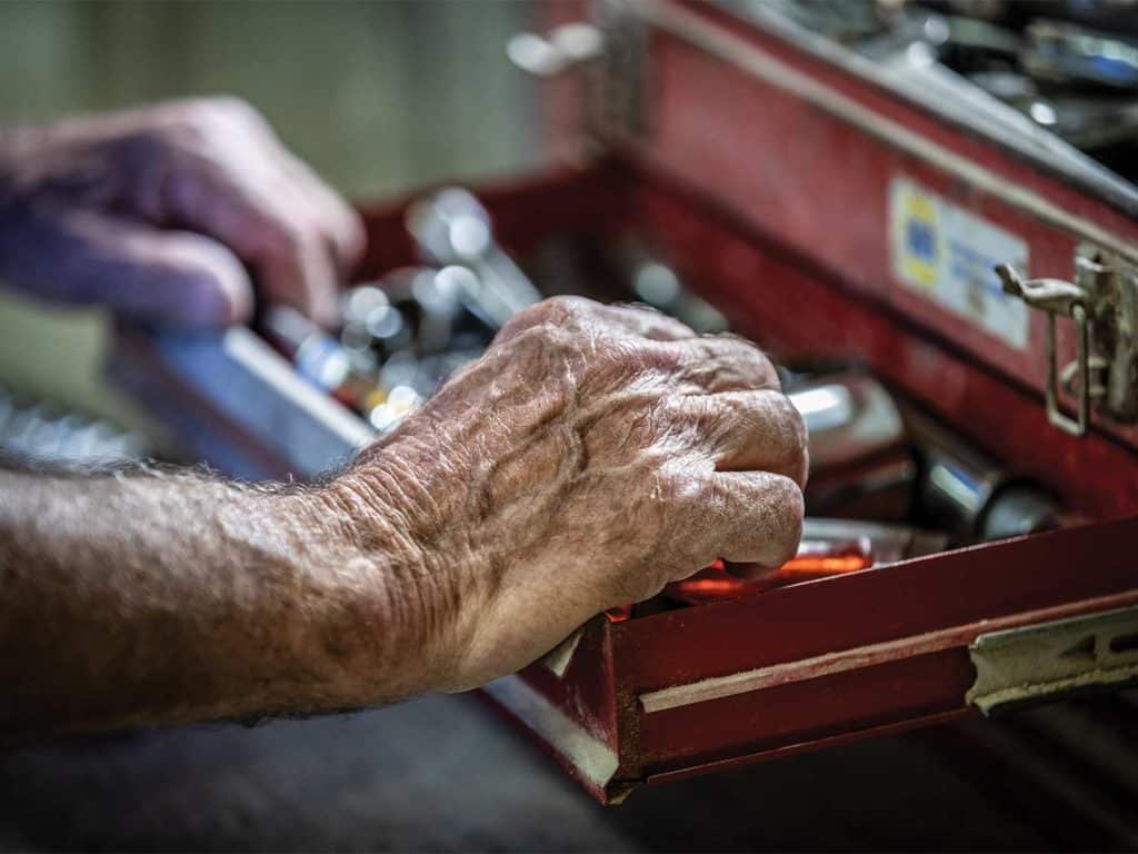 A hand reaching into a toolbox.