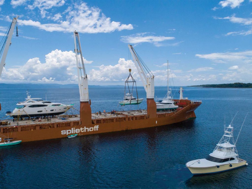 Two boats being loaded onto a large shipping barge.