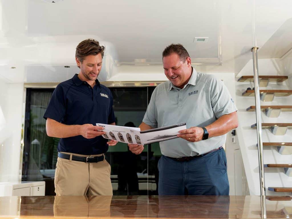 Two men standing and looking over paperwork.