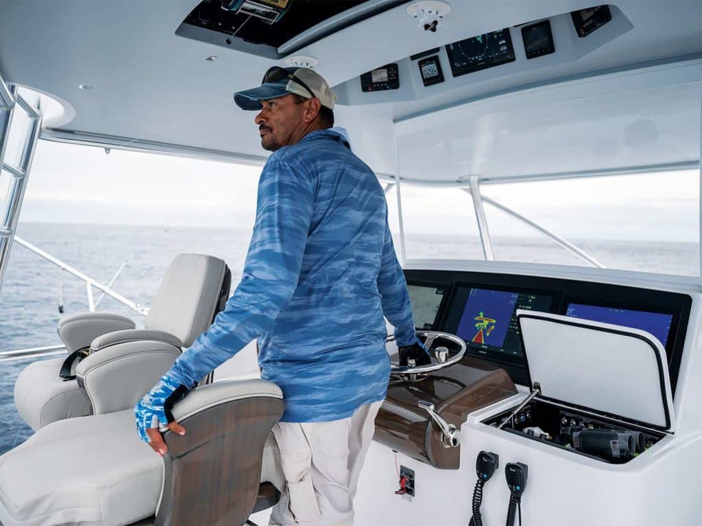A boat captain standing at the helm of a sport-fishing boat.