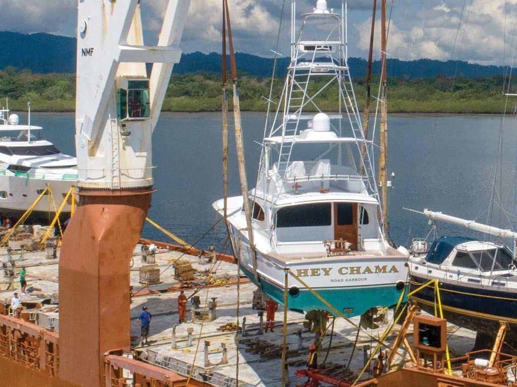 Two boats being loaded onto a large shipping barge.