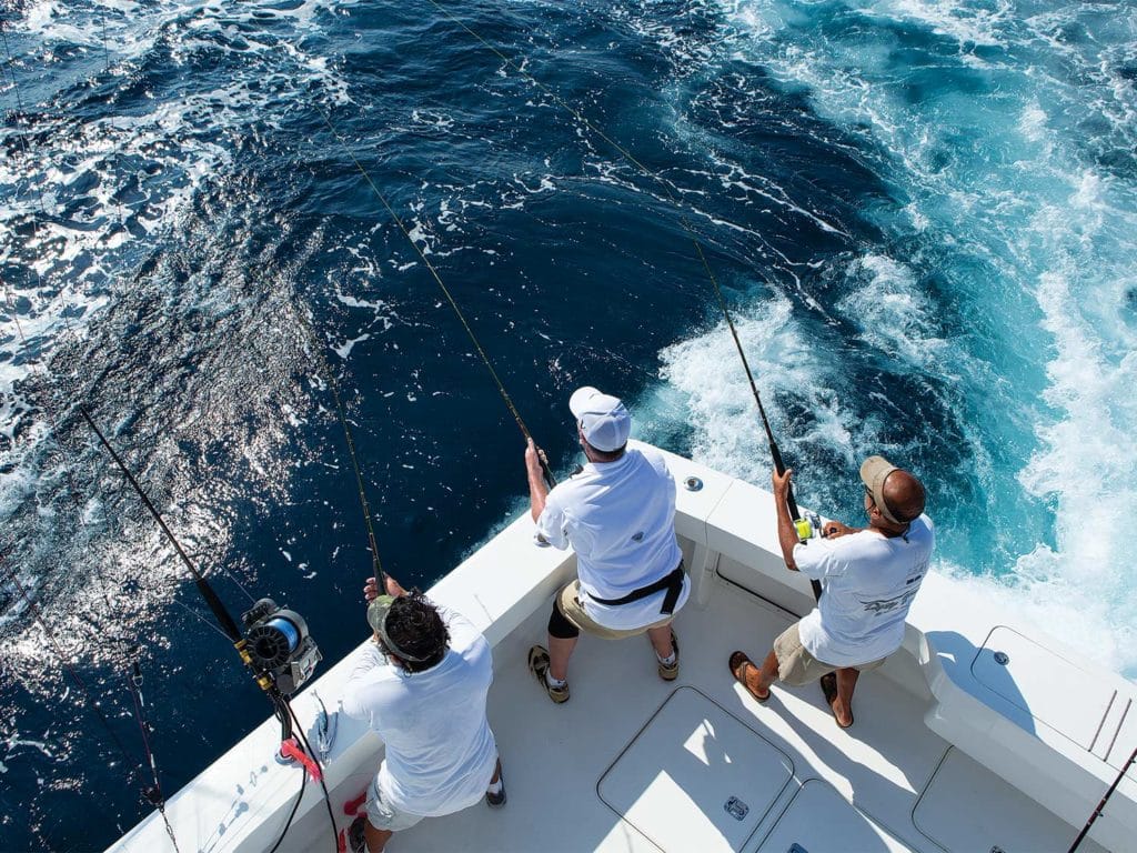 Three sport-fishing anglers fishing in a boat deck.