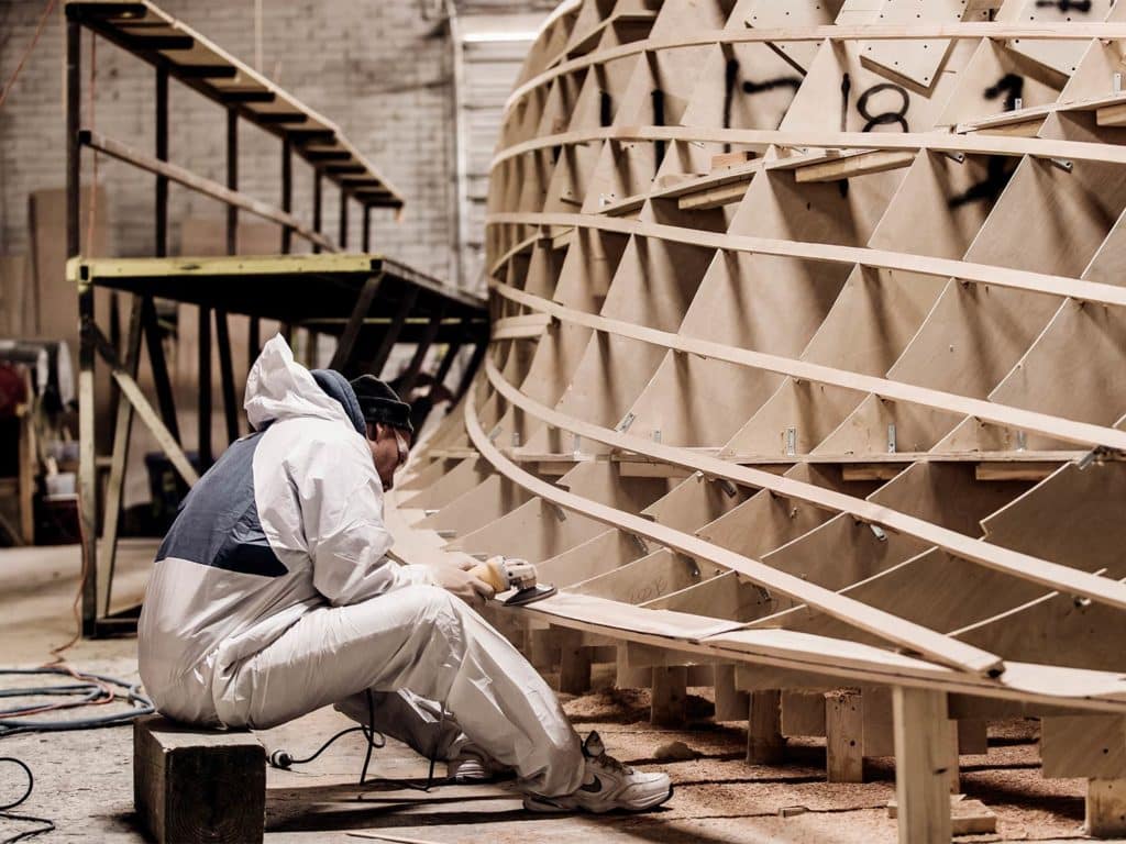 A boat builder working on a hull.