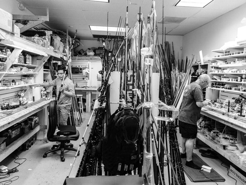 Two workers building custom fishing rods in a workroom.