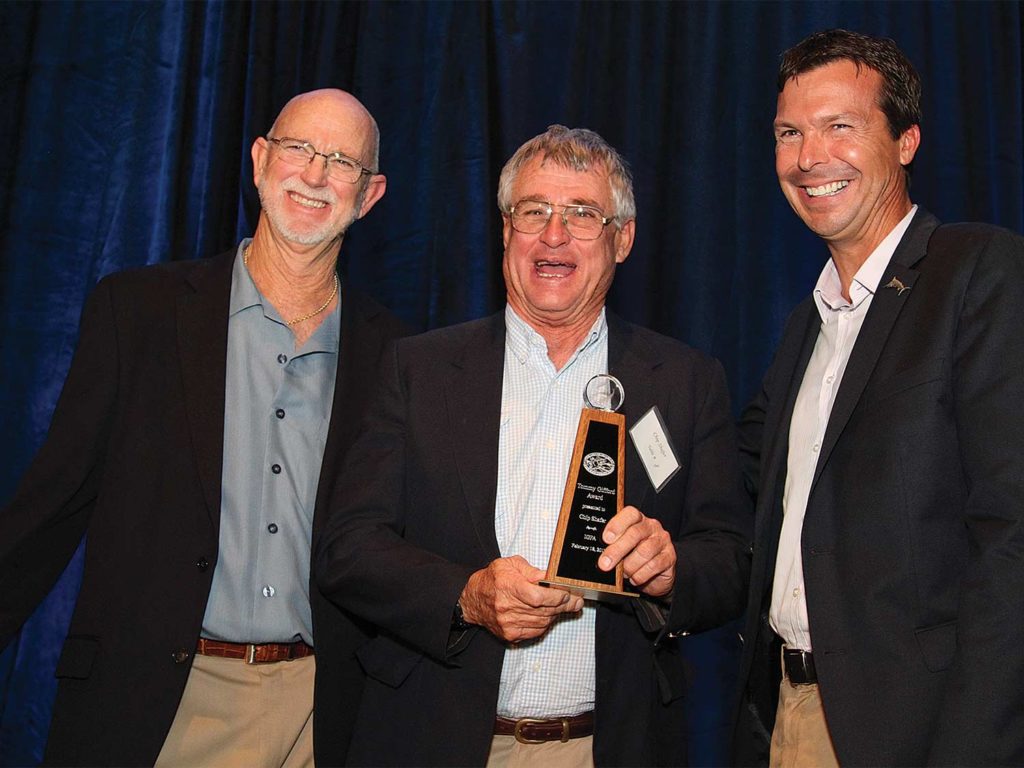 Three men standing at an Awards Ceremony.