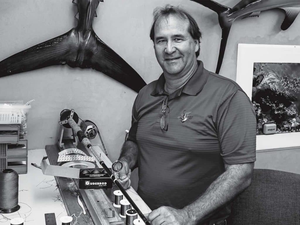 A man standing in a custom fishing rod warehouse.