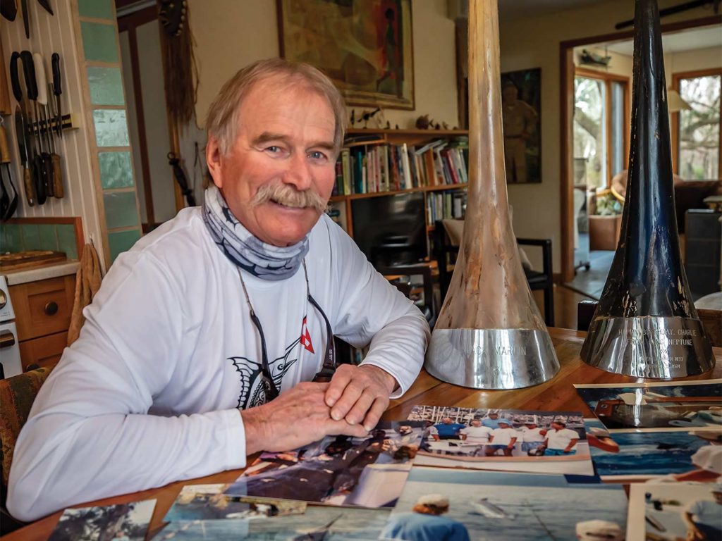 Chalres Perry at a table of newspaper clippings and trophies.