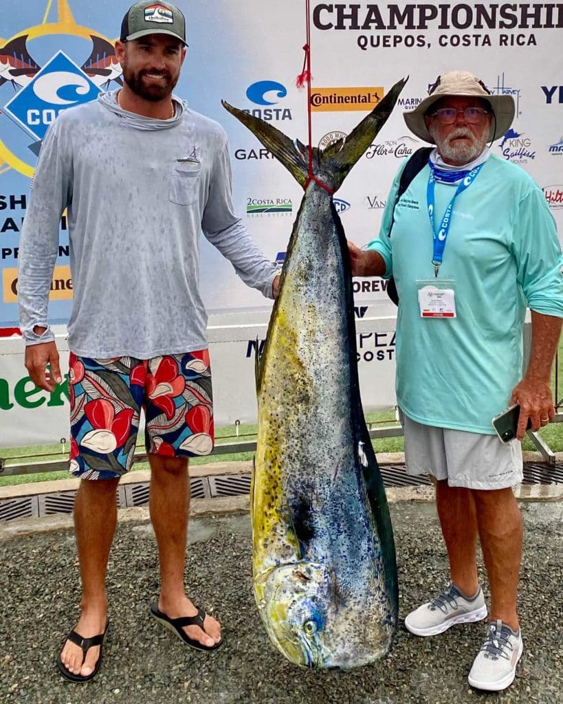 Two anglers holding up large dorado fish.