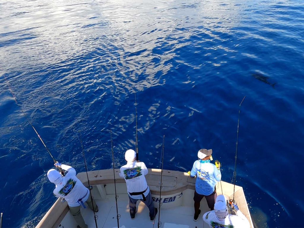 Three sport-fishing anglers on a boat.