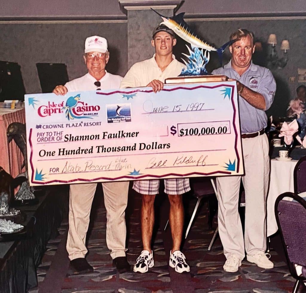 Three men holding up an awards check at a fishing tournament.