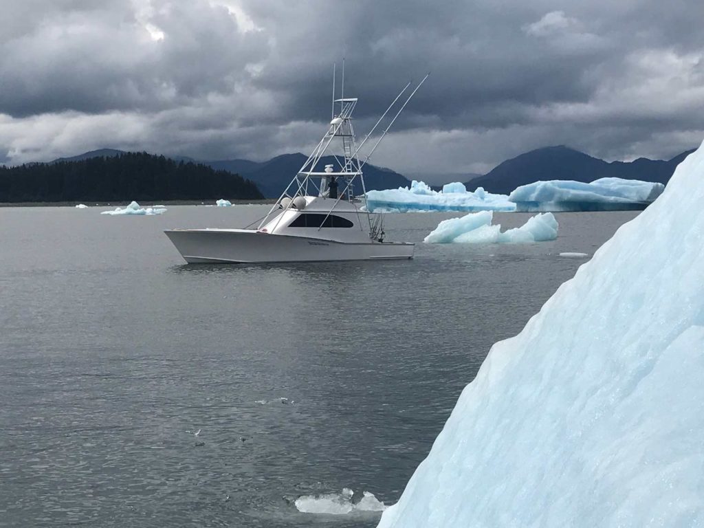 A sport-fishing boat on the water surrounded by glaciers.