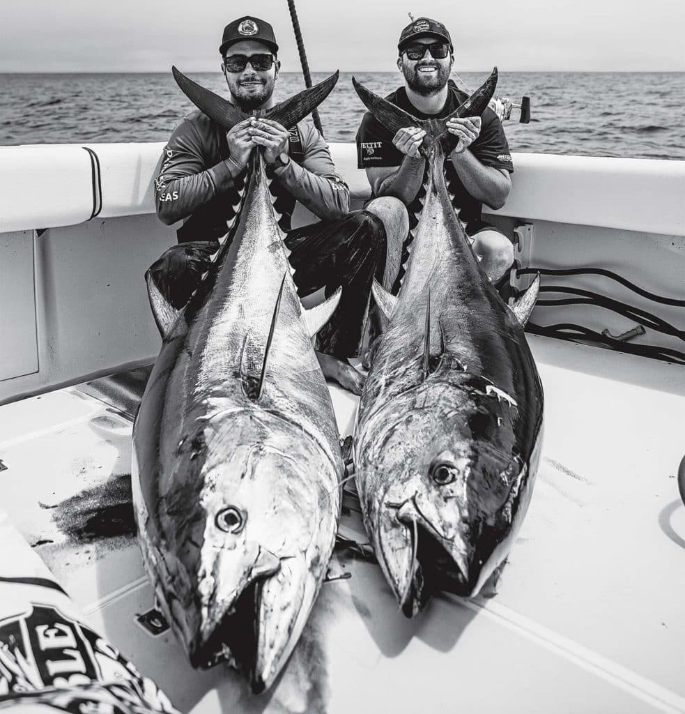 Large bluefin tuna being held by two anglers.