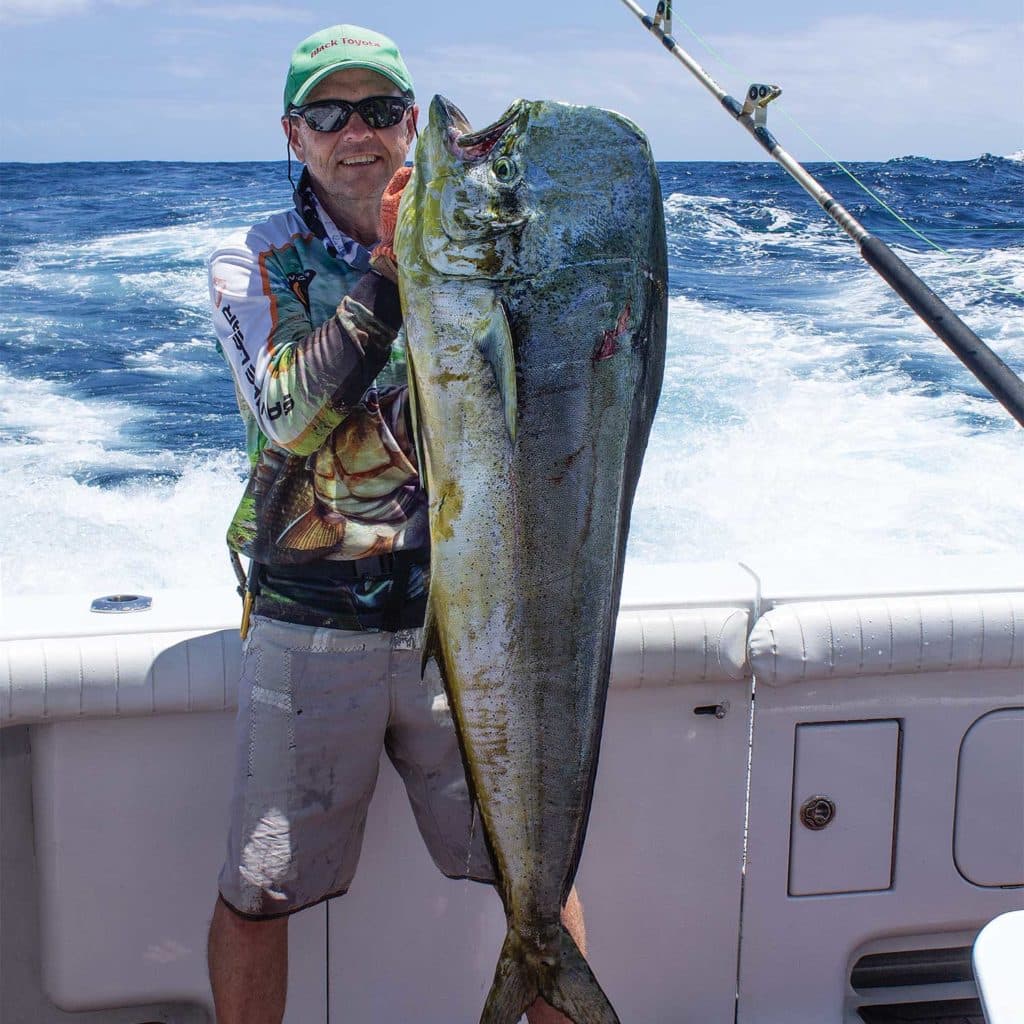 A sport-fishing angler holding up a dolphin fish.