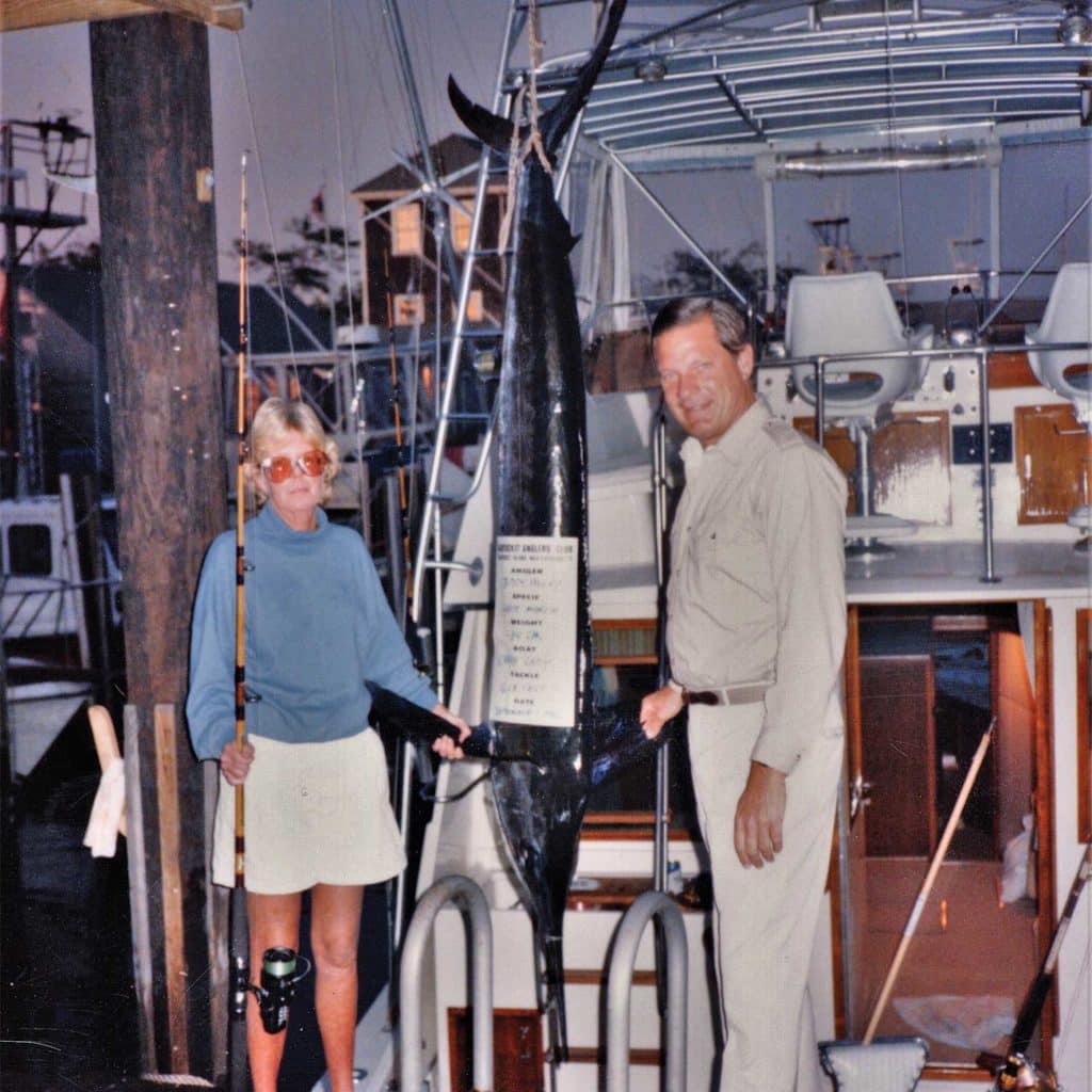 A man and woman standing next to a white marlin.
