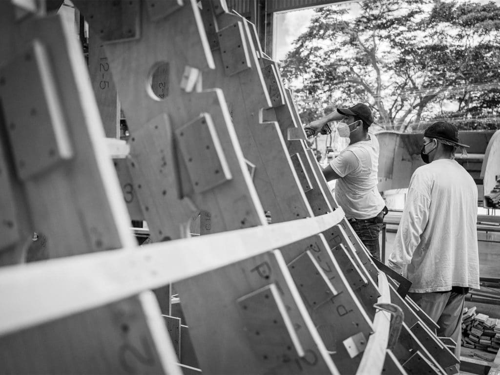 A black and white image of two workers building a boat hull.