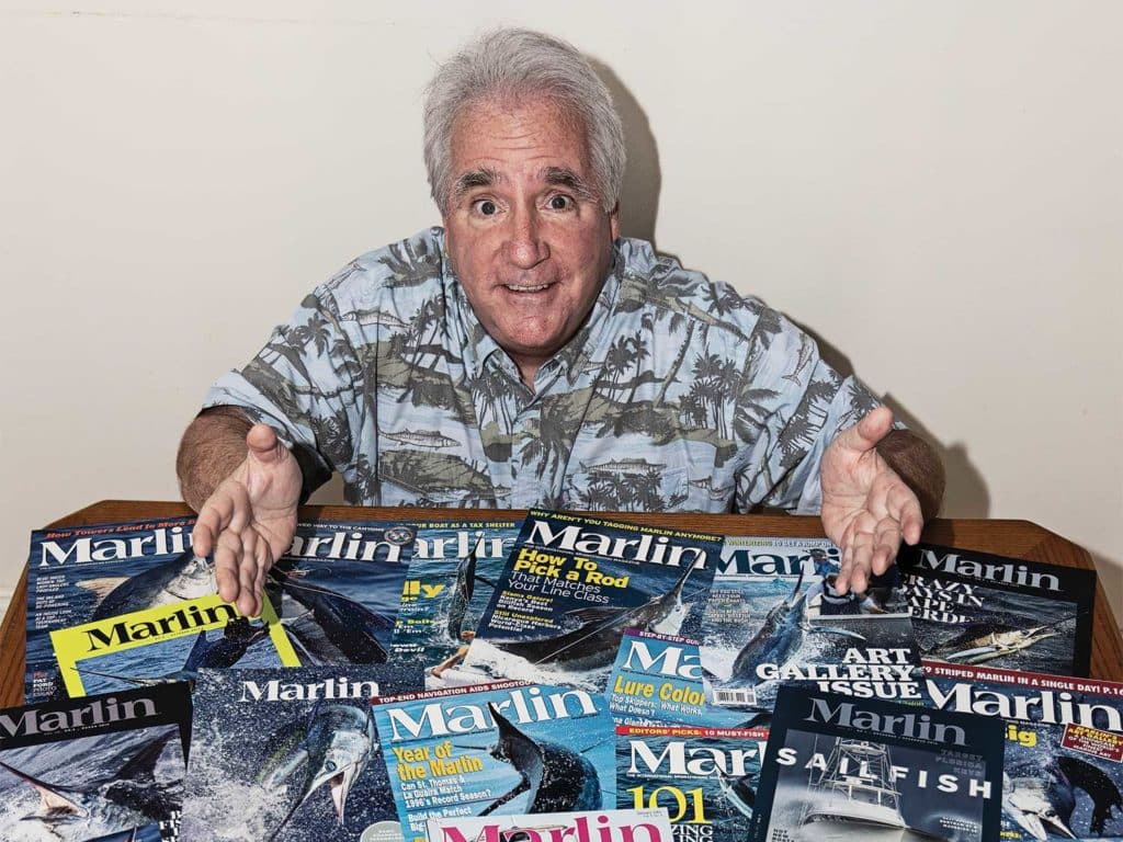 Richard Gibson sitting at a table covered with Marlin magazines.