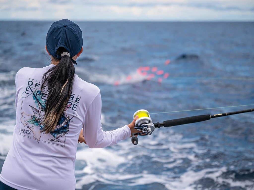 A view of a woman fishing off the back of a sport-fishing boat.