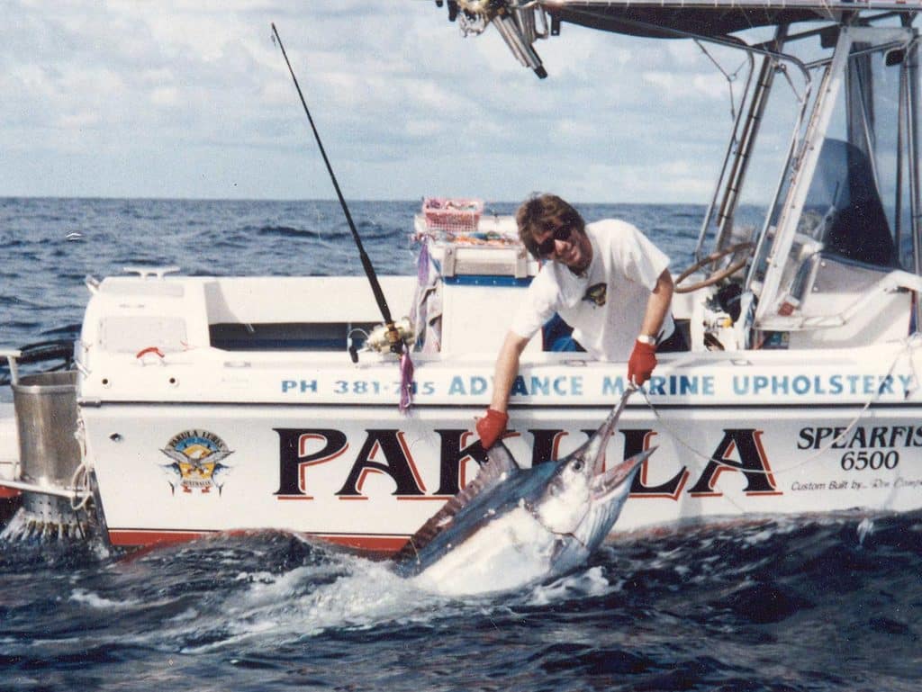 A fishing crew pulls a marlin boatside.