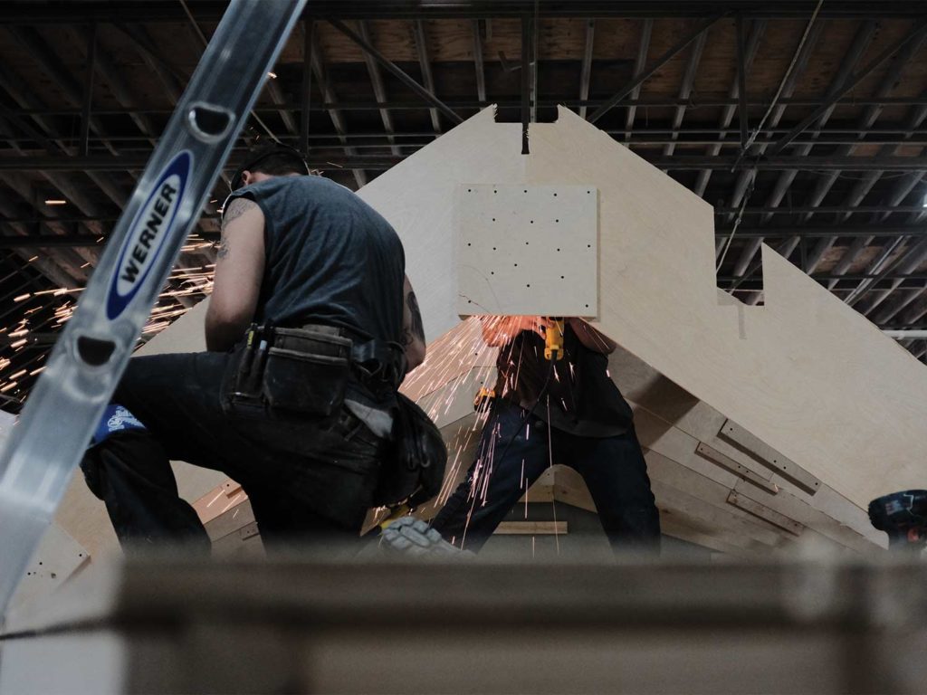 A boat builder grinding and cutting metal for a boat build.