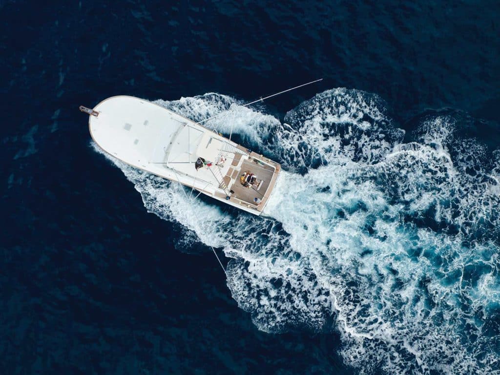 Top-down view of a sport-fishing boat cruising across the water.