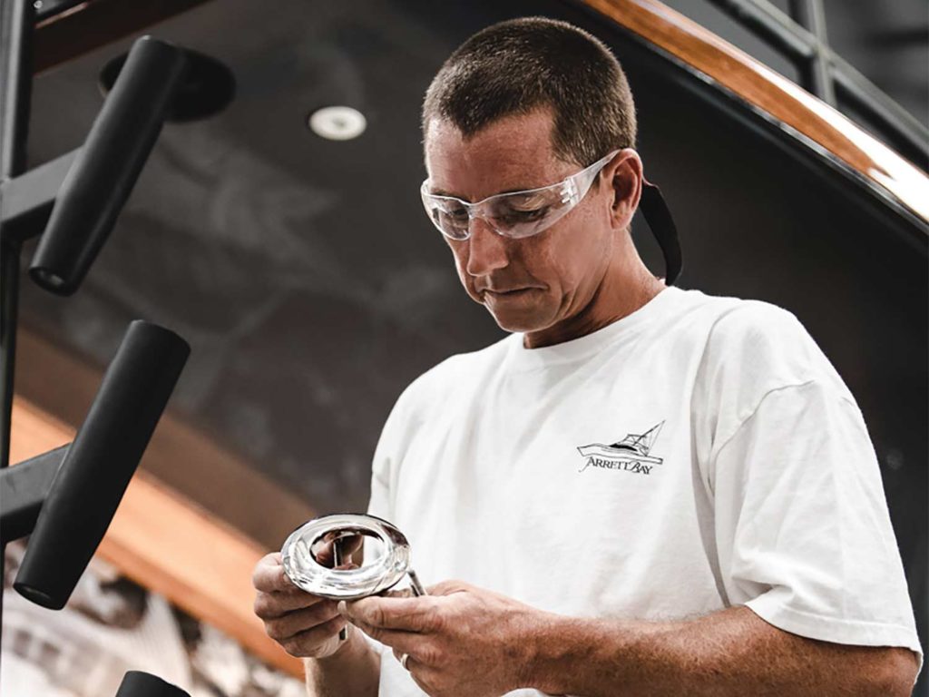 A custom boat builder holding a metal band.