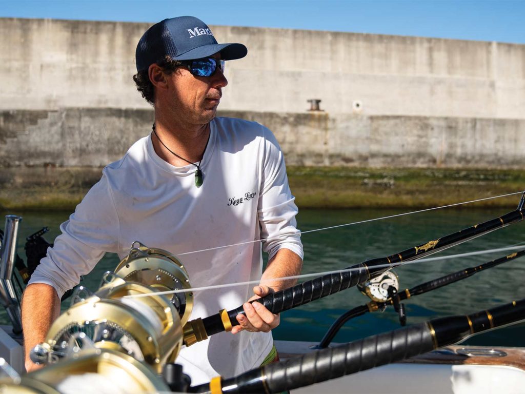 A crewmate prepares a fishing reel in the cockpit.