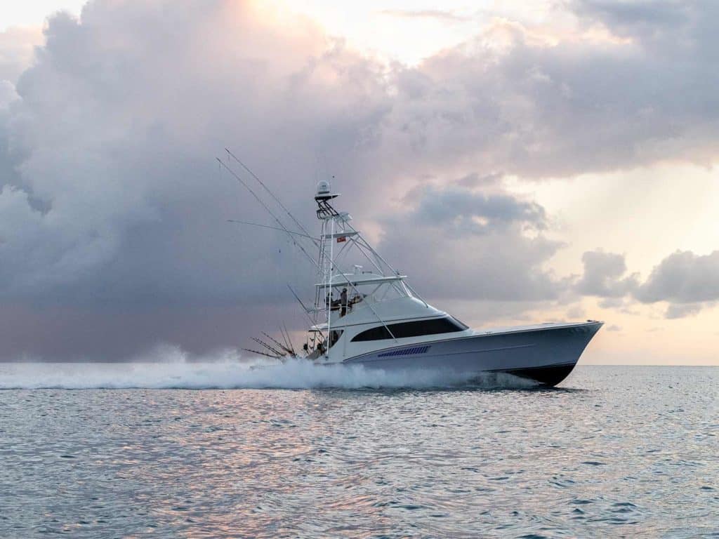 A Titan Custom Yacht cruising across the water at sunset, clouds on the horizon.