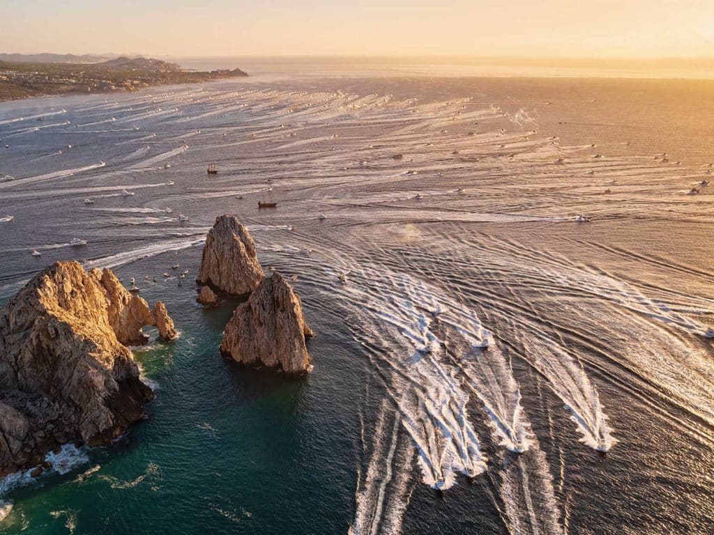 Aerial view of a massive fleet of sport-fishing boats cruising out of the bay.